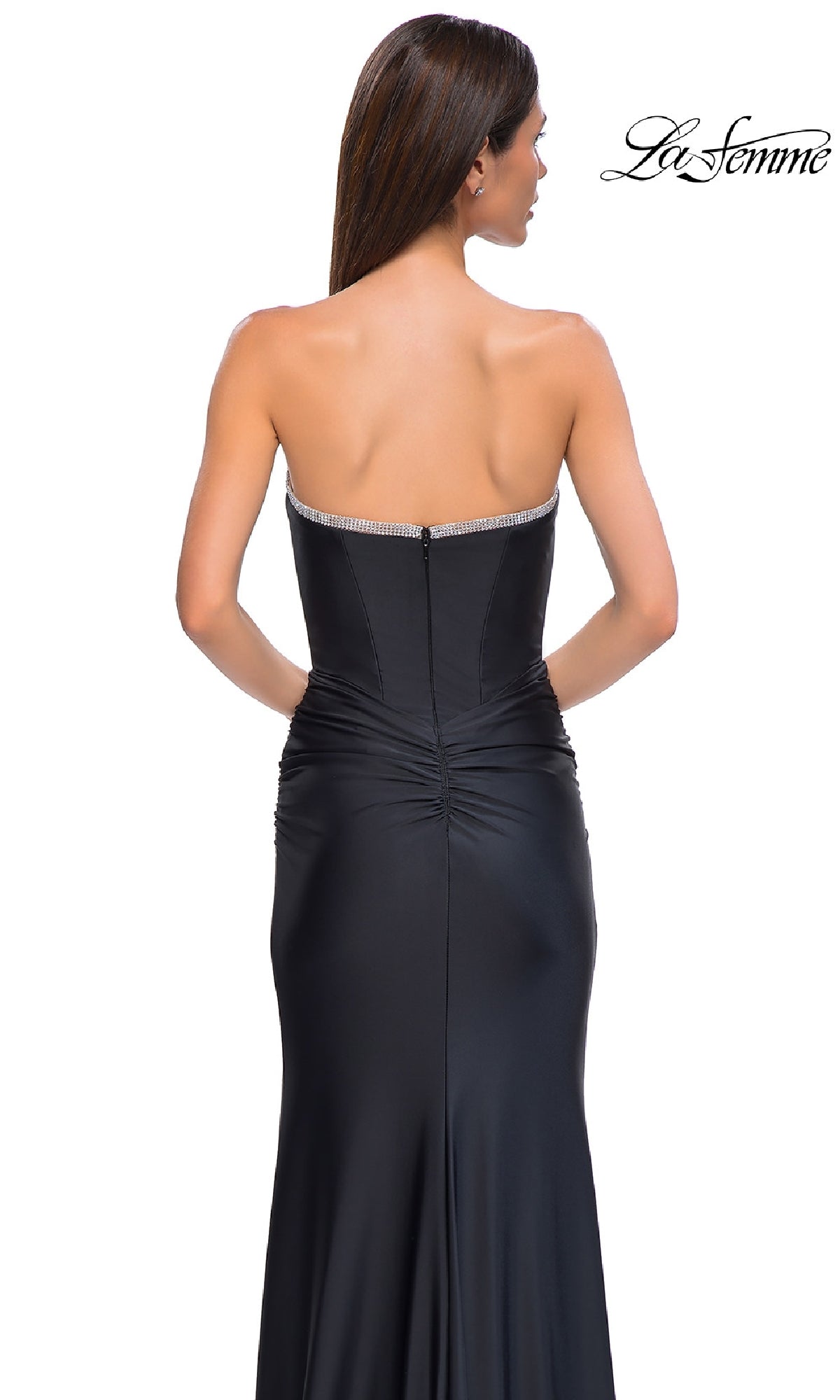 A woman models the Bead-Trimmed Strapless Prom Gown: La Femme 32756, a fitted black gown with a beaded top, ruched waist, and smooth floor-length skirt, elegantly showcased from the back.